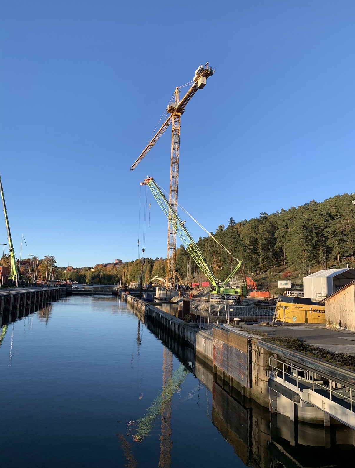 Byggarbetsplats vid Södertälje sluss med kranar vid vattnet.